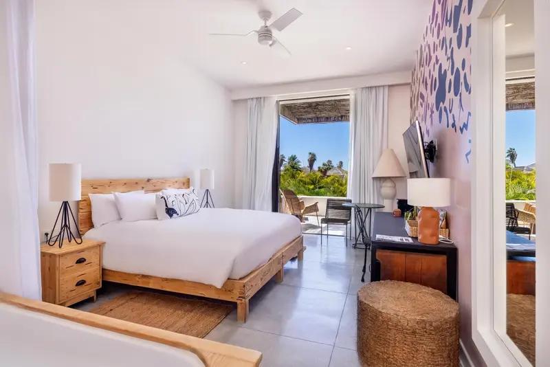 Une chambre lumineuse avec un grand lit et une vue sur la végétation.
