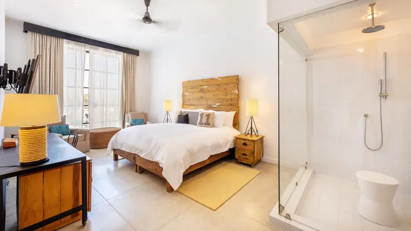 Une chambre lumineuse avec un grand lit et une douche à l'italienne.