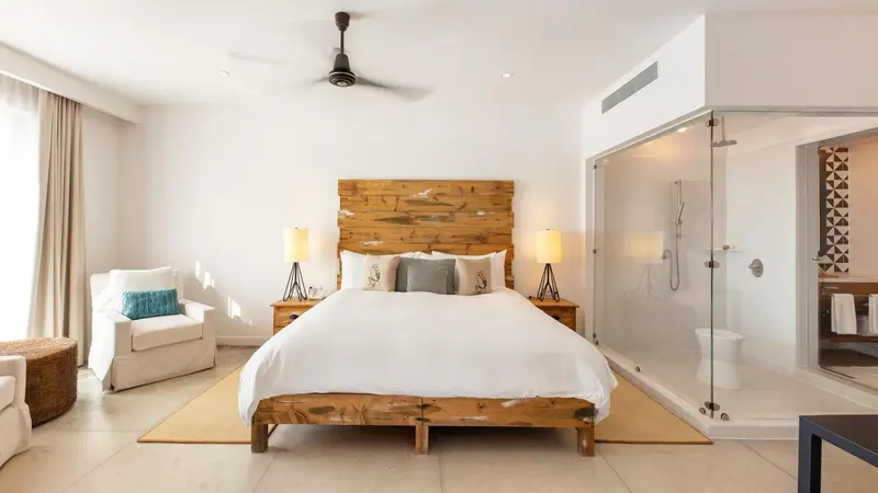 Une chambre lumineuse avec un grand lit et une douche vitrée.