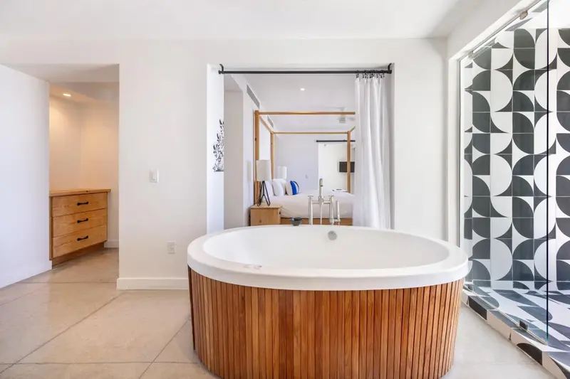 Une baignoire ronde en bois se trouve dans une salle de bain lumineuse.