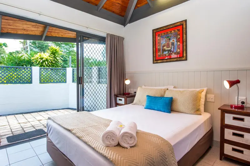 Une chambre lumineuse avec un grand lit et un accès à une terrasse.