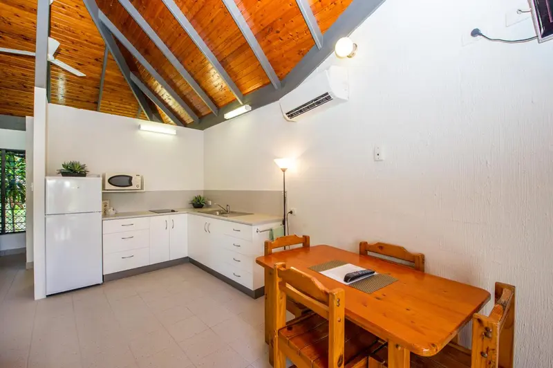 Une cuisine lumineuse s'ouvre sur une petite salle à manger en bois.