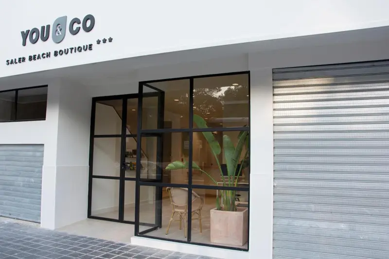 Façade d'un commerce avec une entrée vitrée et une plante en pot.