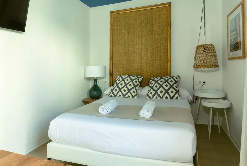 Une chambre lumineuse avec un grand lit recouvert de coussins décoratifs.