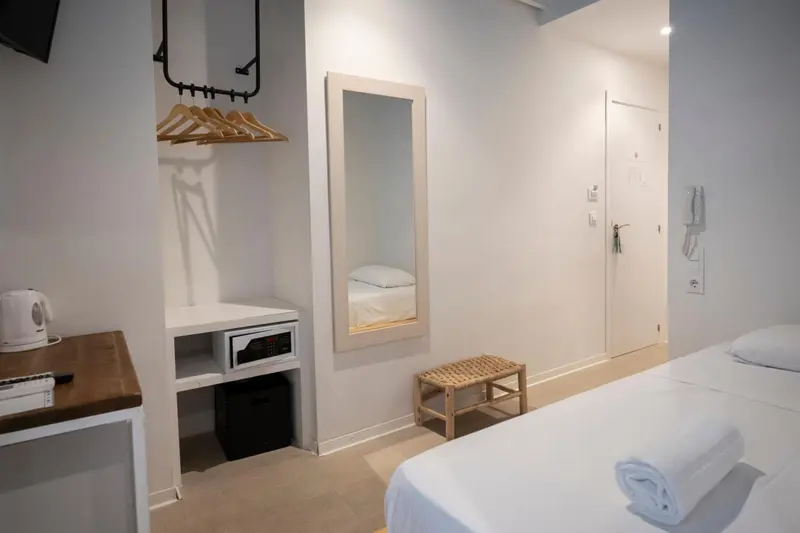 Une chambre lumineuse avec un lit fait et un espace rangement.