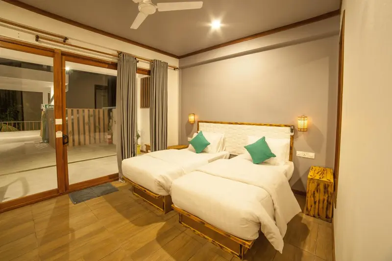 Une chambre lumineuse avec deux lits simples et un accès à une terrasse.