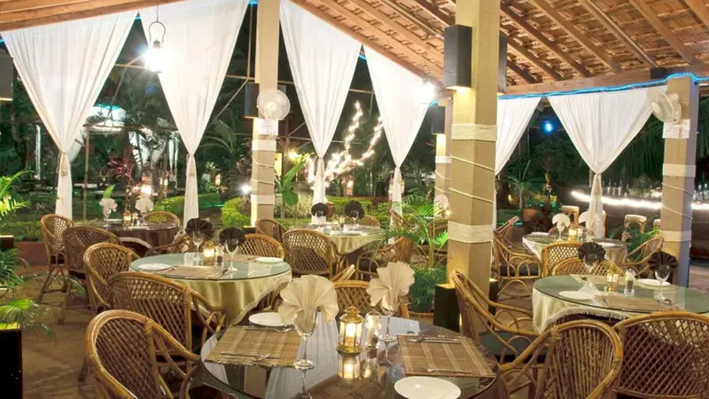 Tables dressées dans une salle à manger extérieure décorée de rideaux blancs.