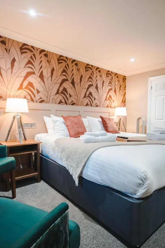 Une chambre d'hôtel avec un grand lit recouvert d'une couverture blanche et de coussins.