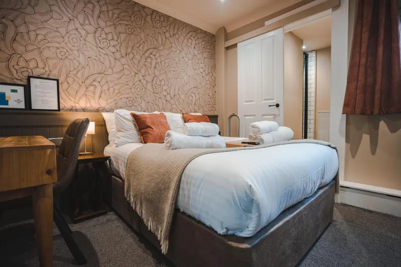 Une chambre avec un lit double et une décoration florale sur les murs.