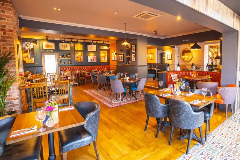 Une salle de restaurant lumineuse avec des tables dressées et des clients.