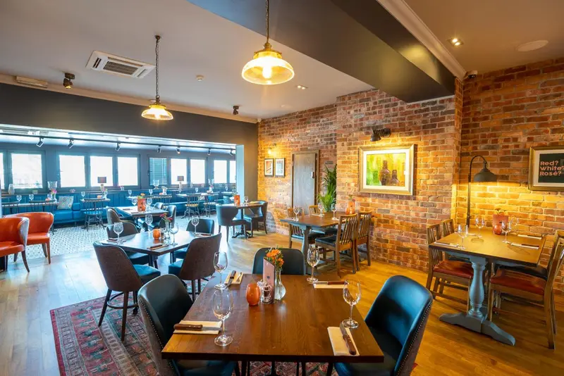Une salle de restaurant lumineuse avec des tables dressées et des clients attablés.