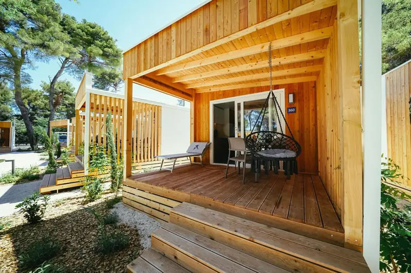 Terrasse en bois devant une habitation en bois clair.