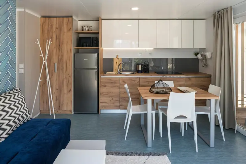 Une cuisine moderne s'ouvre sur un coin repas avec table et chaises.