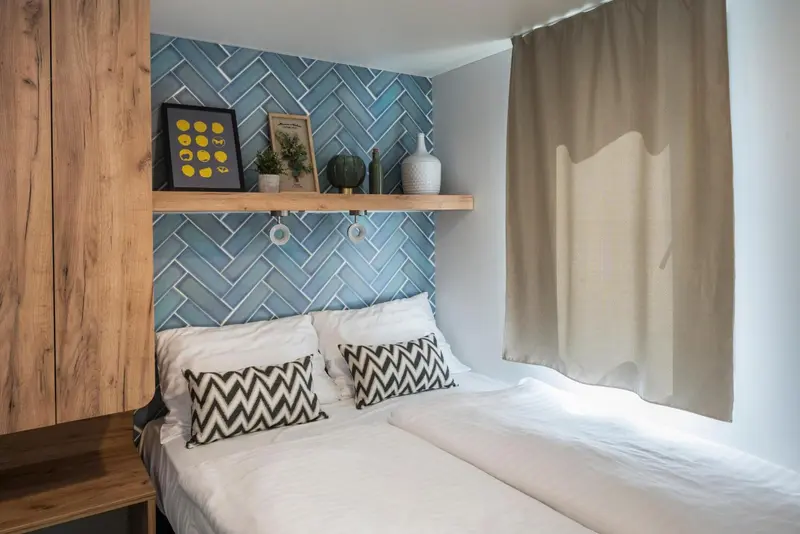 Une chambre avec un lit double et un mur décoratif en mosaïque bleue.