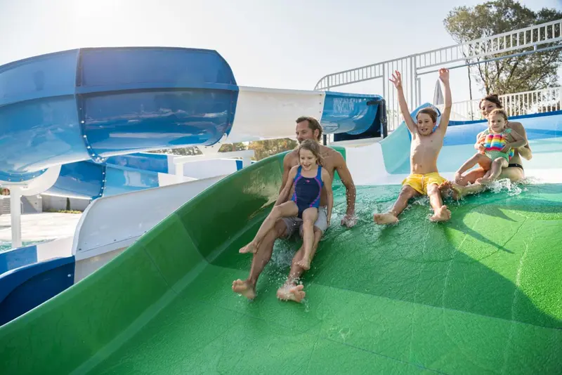 Une famille descend une toboggan aquatique vert et bleu.