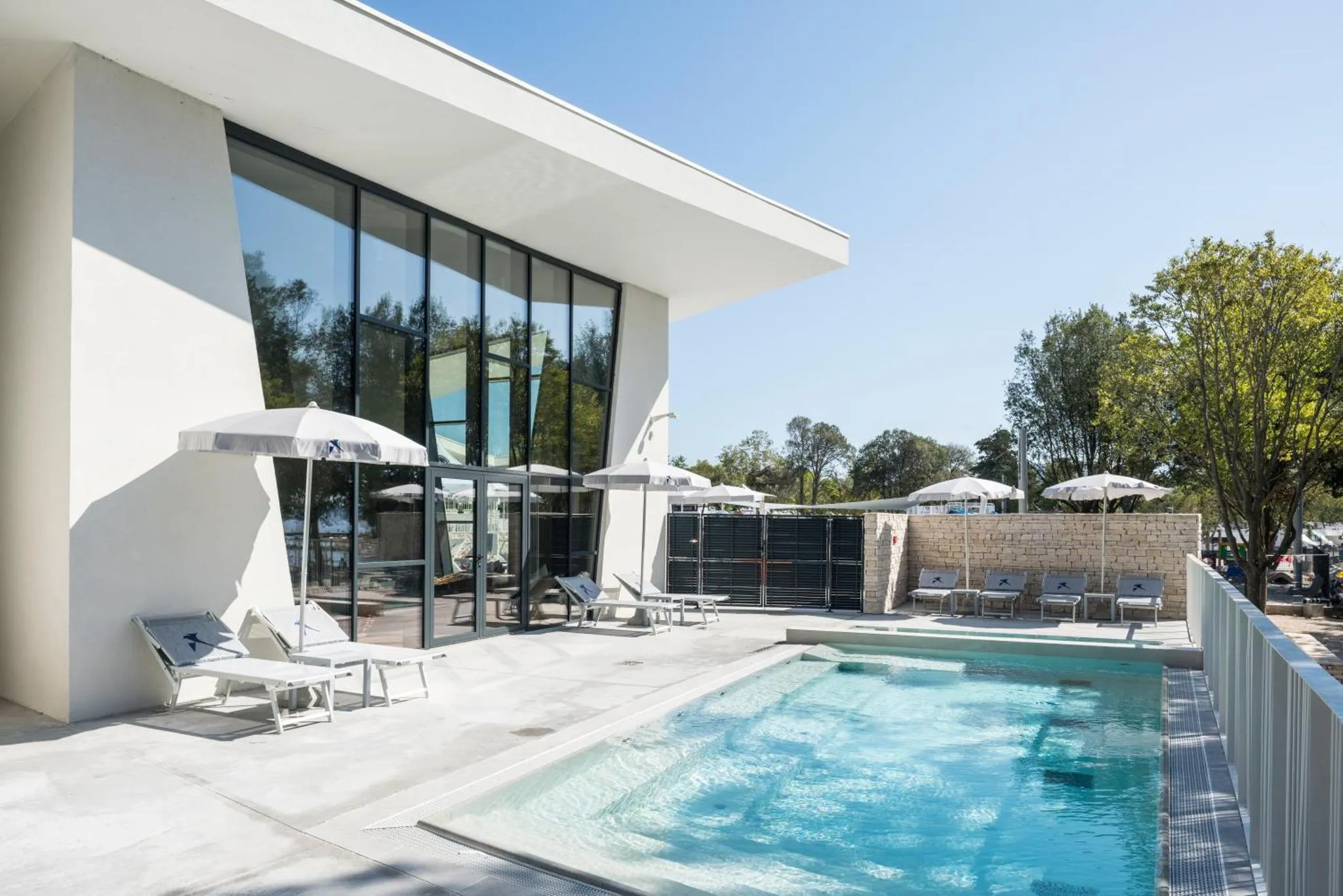 Terrasse avec transats et piscine devant un bâtiment moderne.