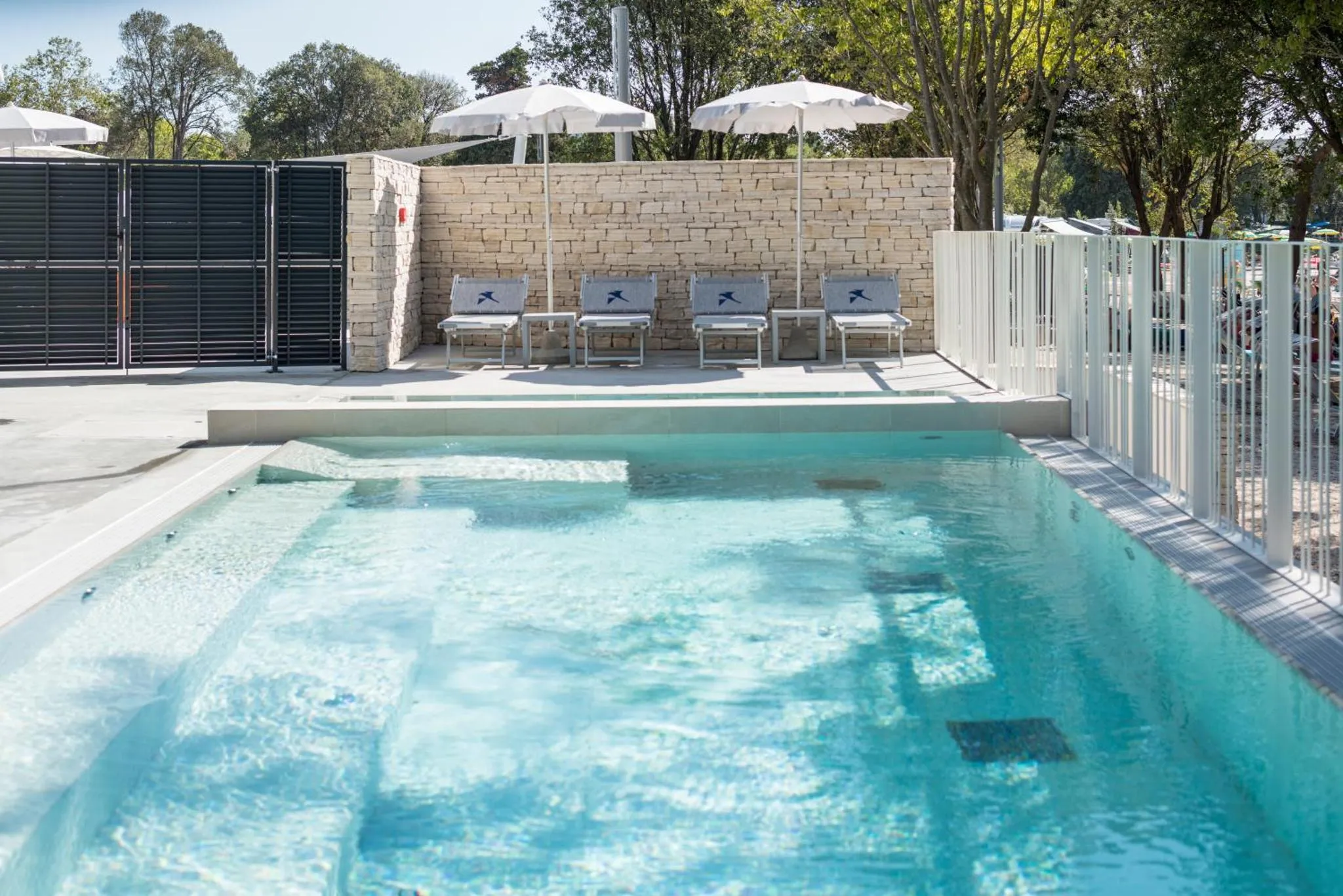 Une piscine rectangulaire avec des transats sur une terrasse ensoleillée.