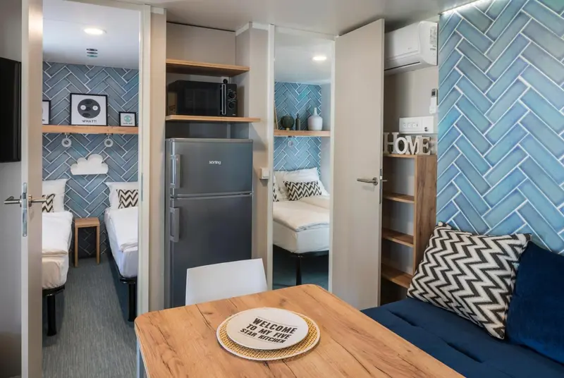 Une kitchenette lumineuse s'ouvre sur un espace de repos avec table et canapé.