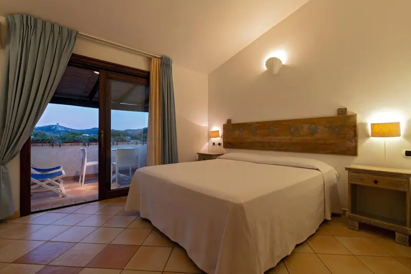 Une chambre lumineuse s'ouvre sur une terrasse avec vue sur la végétation.