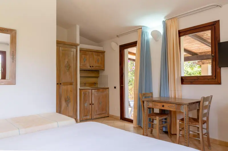 Une pièce lumineuse avec un lit, un coin repas et des meubles en bois.