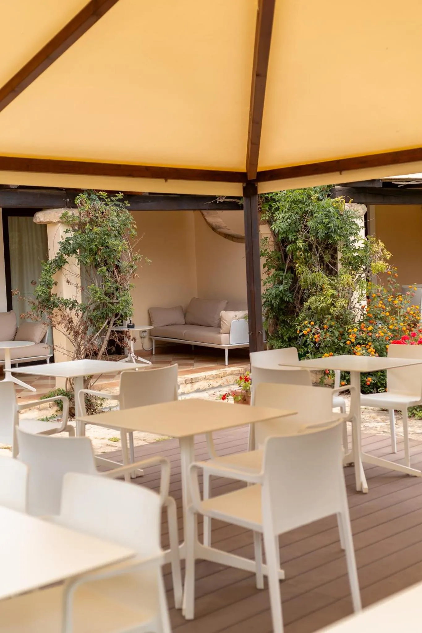 Tables et chaises blanches disposées sur une terrasse ombragée.