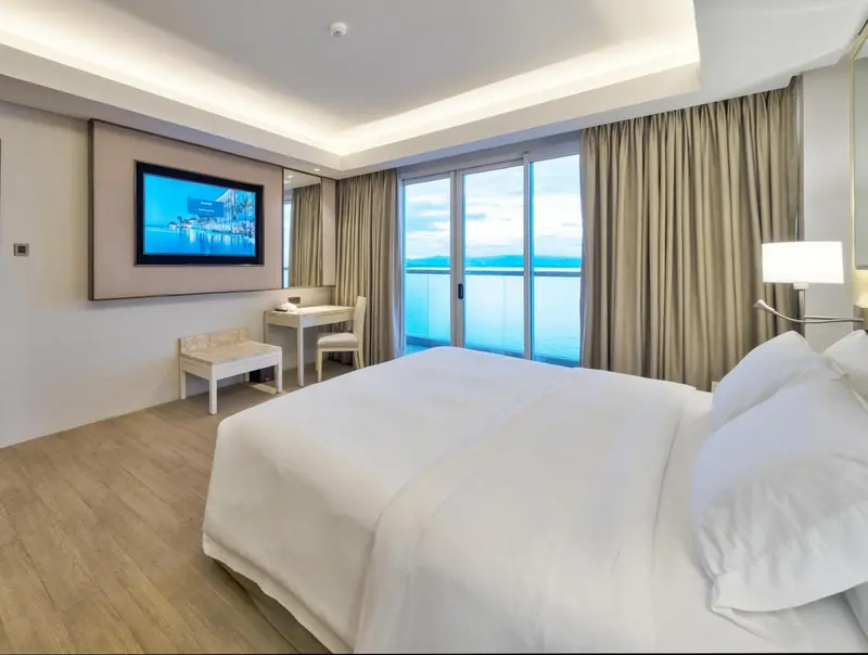Chambre lumineuse avec un grand lit et une vue sur la mer.