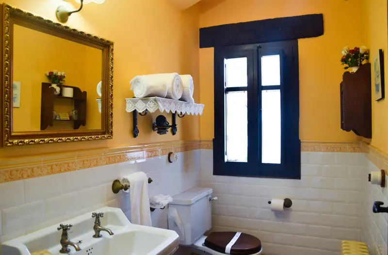 Une salle de bain lumineuse avec des murs jaunes et des carreaux blancs.