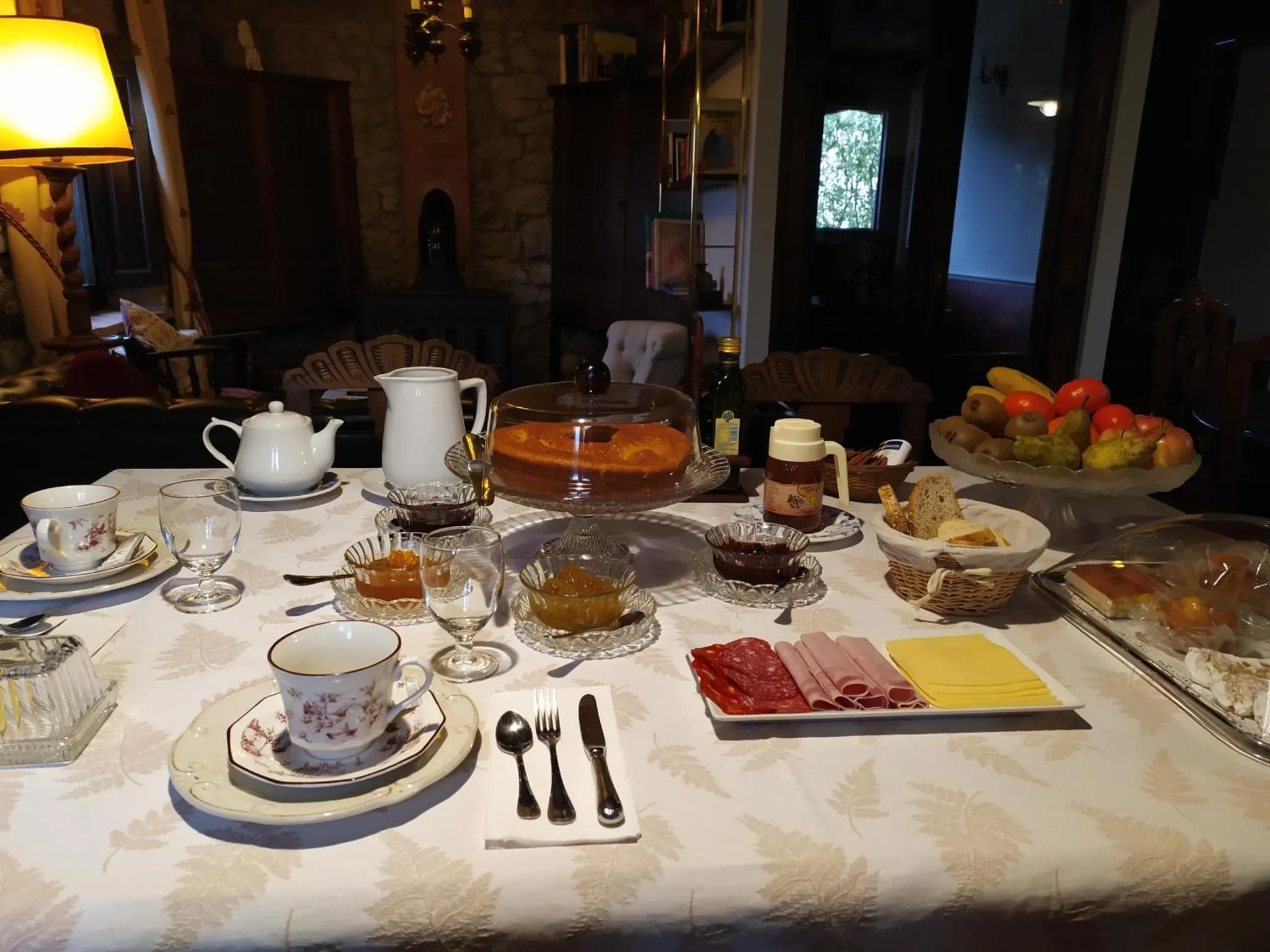 Une table est dressée pour le petit-déjeuner avec des viennoiseries, des fruits et des boissons.