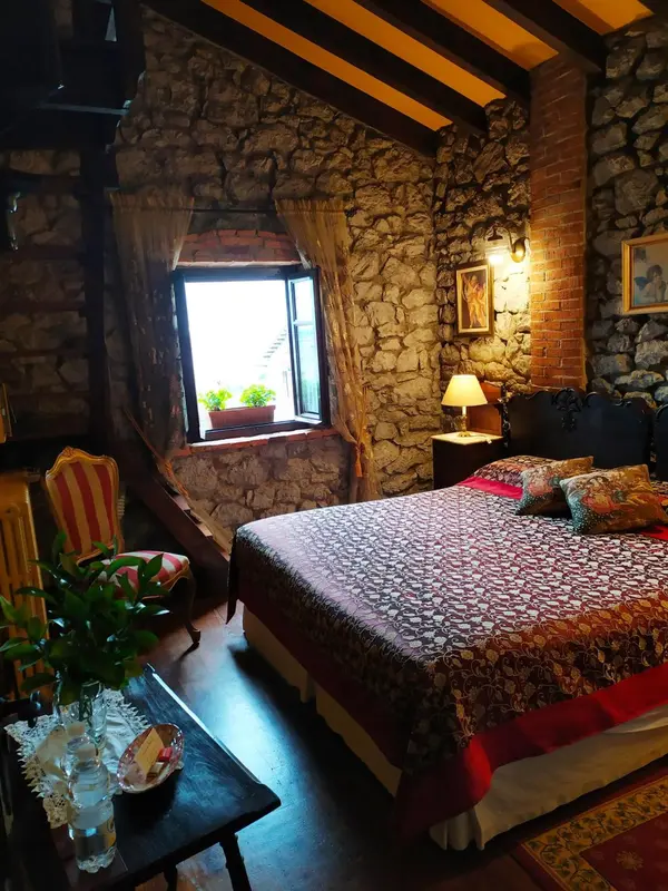 Une chambre rustique avec un lit recouvert d'une courtepointe et une fenêtre donnant sur un jardin.