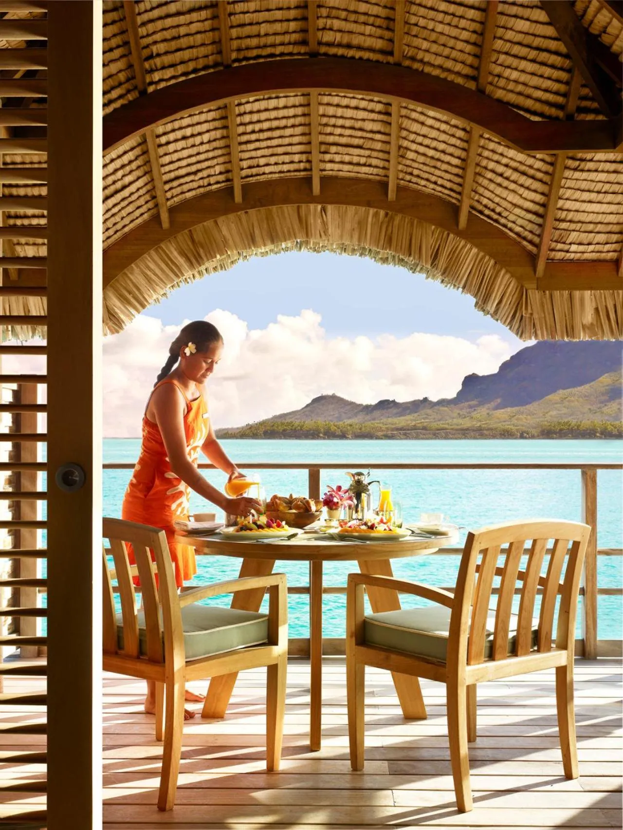 Une personne prépare un repas sur une terrasse avec vue sur la mer.