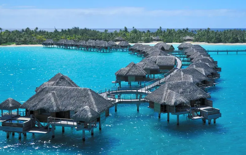 Bungalows sur pilotis au-dessus d'une eau turquoise et d'un lagon.