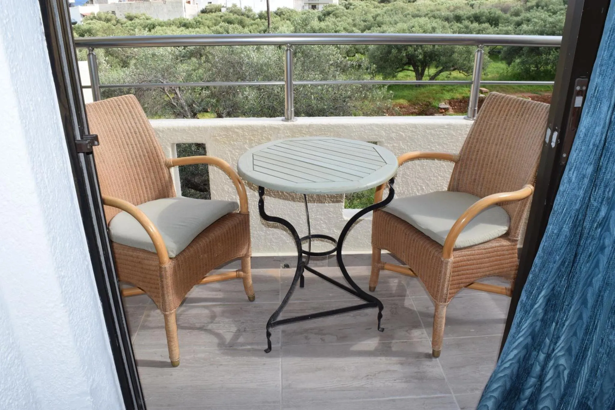 Deux fauteuils en osier et une petite table ronde sur une terrasse.