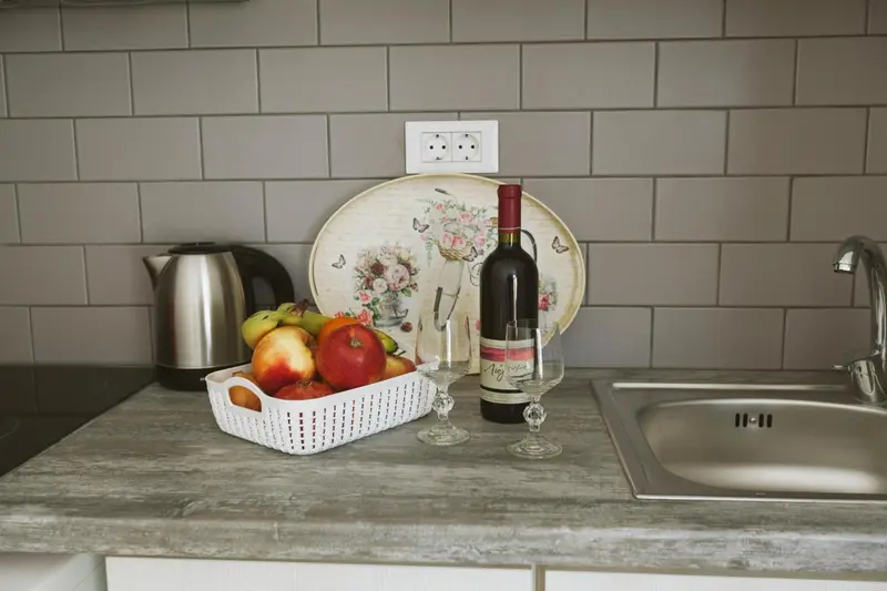 Une nature morte de fruits et une bouteille de vin sur un plan de travail de cuisine.