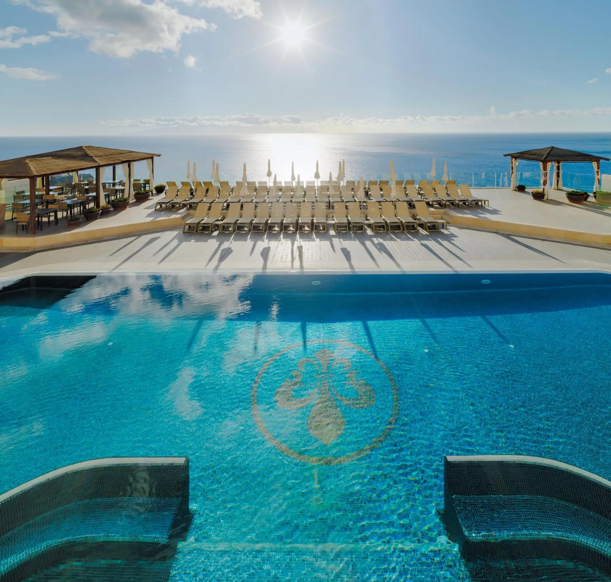 Terrasse avec transats et piscine surplombant la mer.