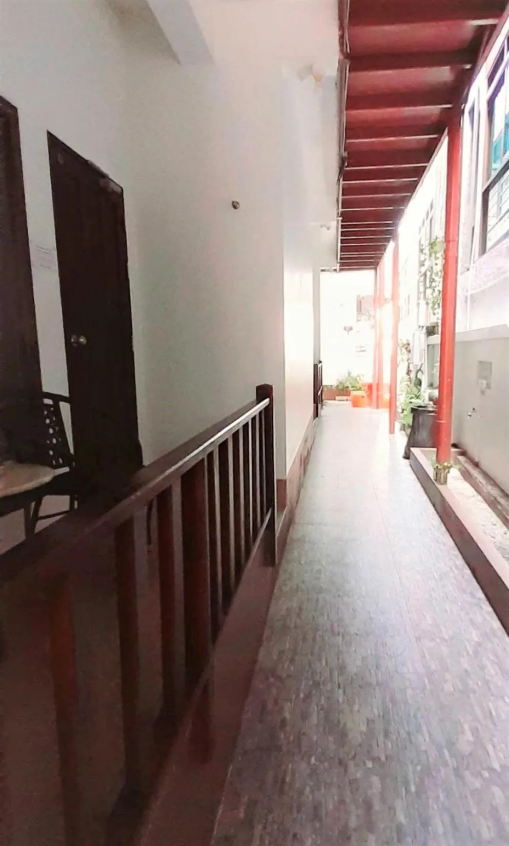 Un couloir intérieur mène vers une cour ombragée.