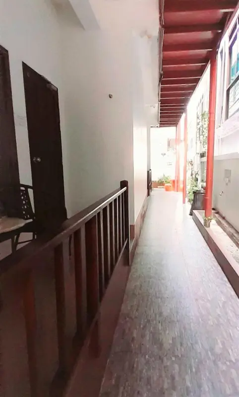Un couloir intérieur mène vers une cour ombragée.