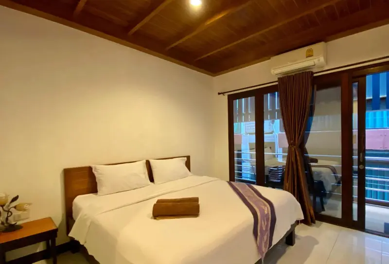 Chambre lumineuse avec un lit double et une porte-fenêtre donnant sur l'extérieur.