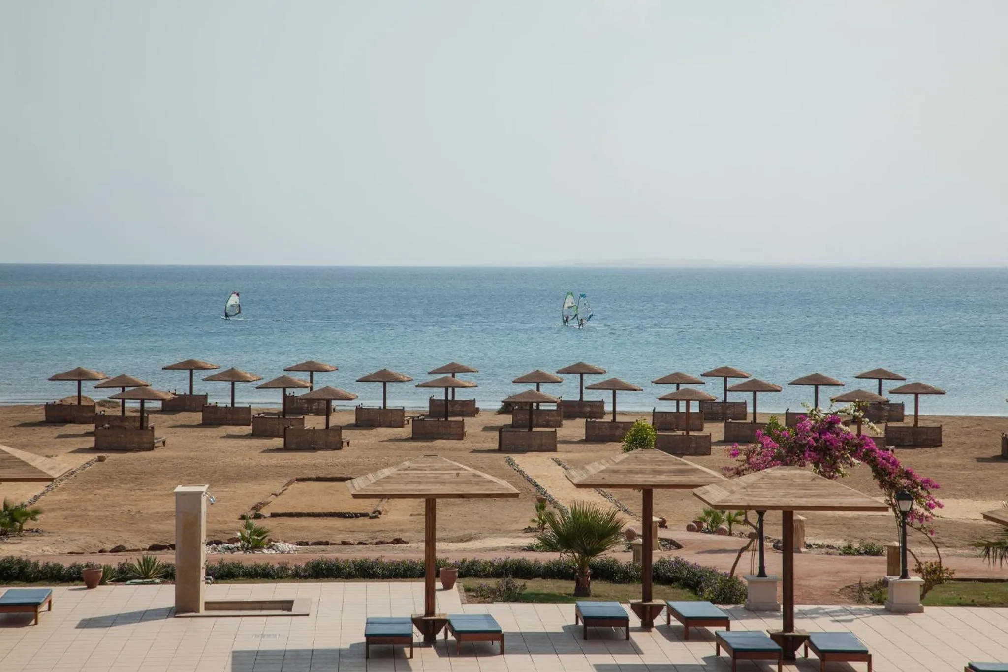 Vue d'une plage avec parasols et transats face à la mer.