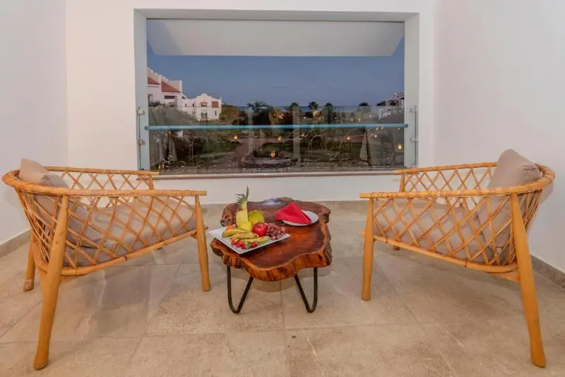 Deux fauteuils en rotin face à une vue sur la mer et un paysage tropical.