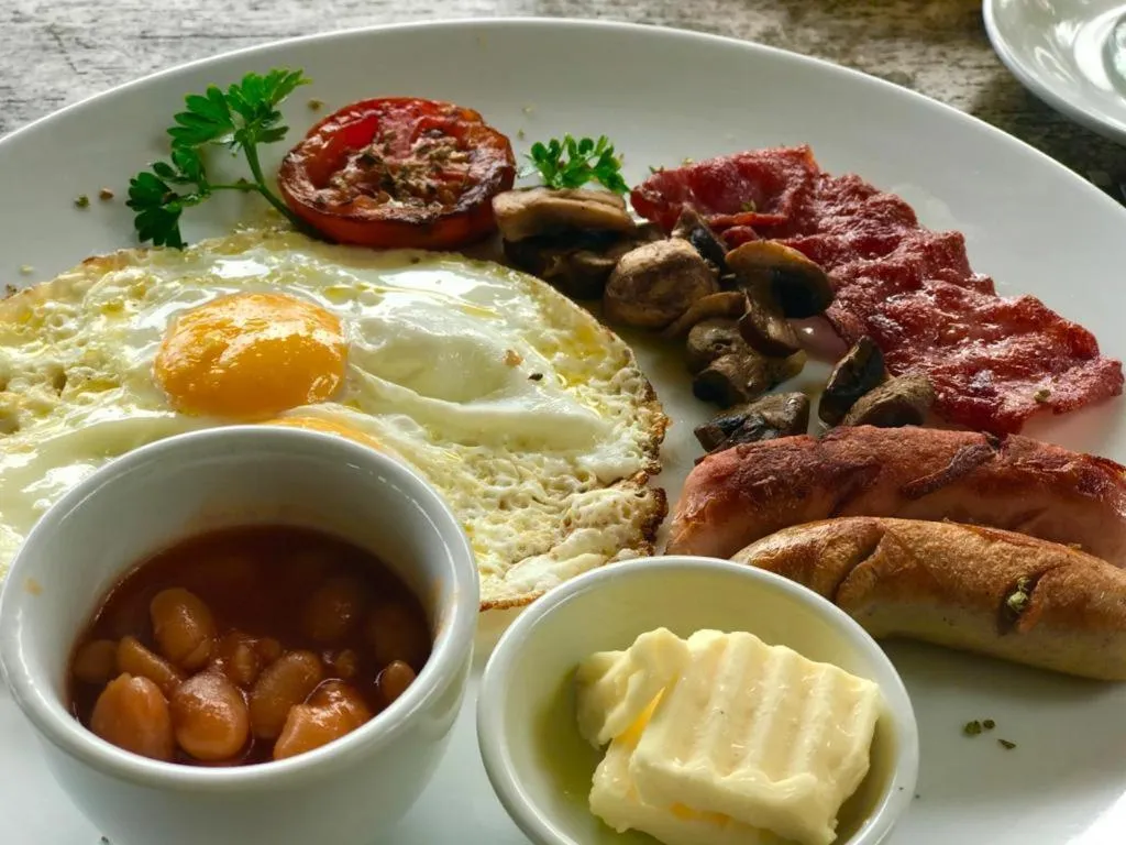 Assiette copieuse avec oeufs au plat, bacon, saucisses et haricots.