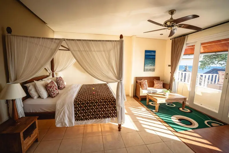 Une chambre lumineuse avec un grand lit à baldaquin et un accès à une terrasse.