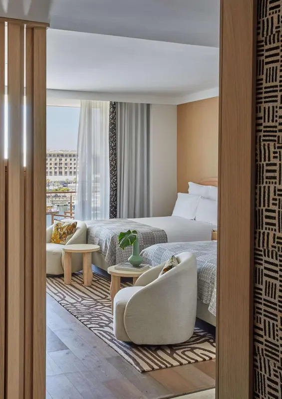 Une chambre lumineuse avec deux lits et un coin salon.