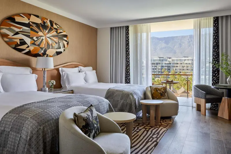 Chambre avec deux lits et espace détente donnant sur un paysage montagneux.