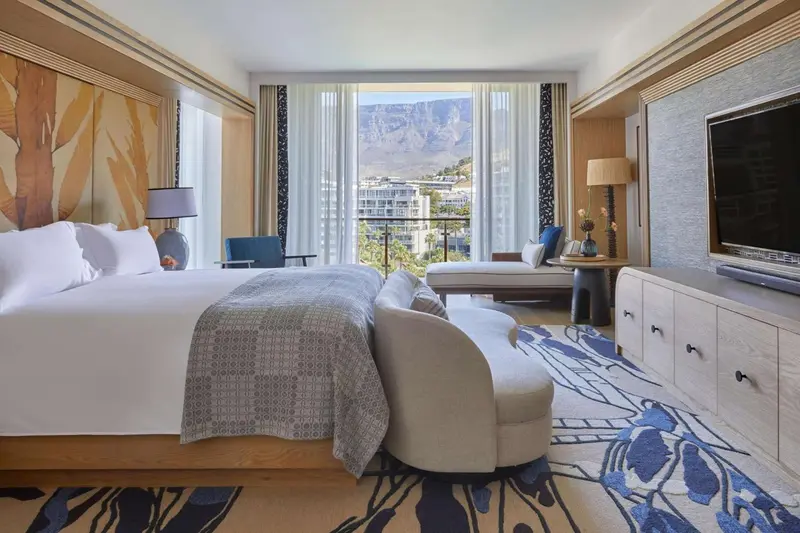 Chambre lumineuse avec un grand lit et un espace détente près de la fenêtre.