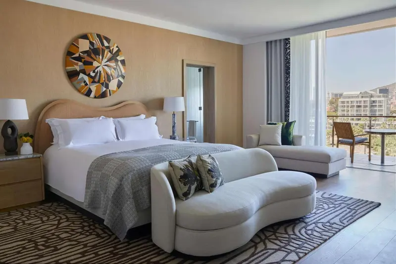 Une chambre lumineuse avec un grand lit et un coin salon donnant sur une terrasse.
