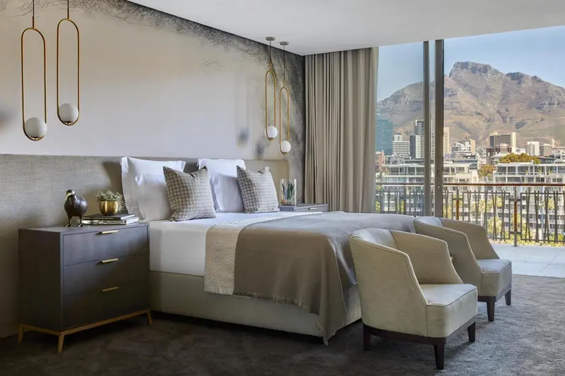 Une chambre lumineuse avec un grand lit et une vue sur la ville et les montagnes.