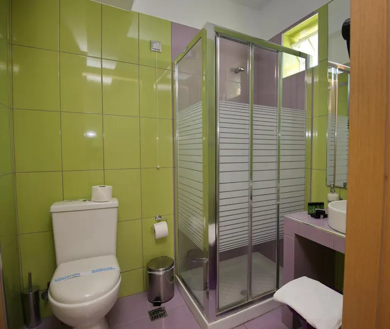 Une salle de bain lumineuse avec douche vitrée et carrelage coloré.