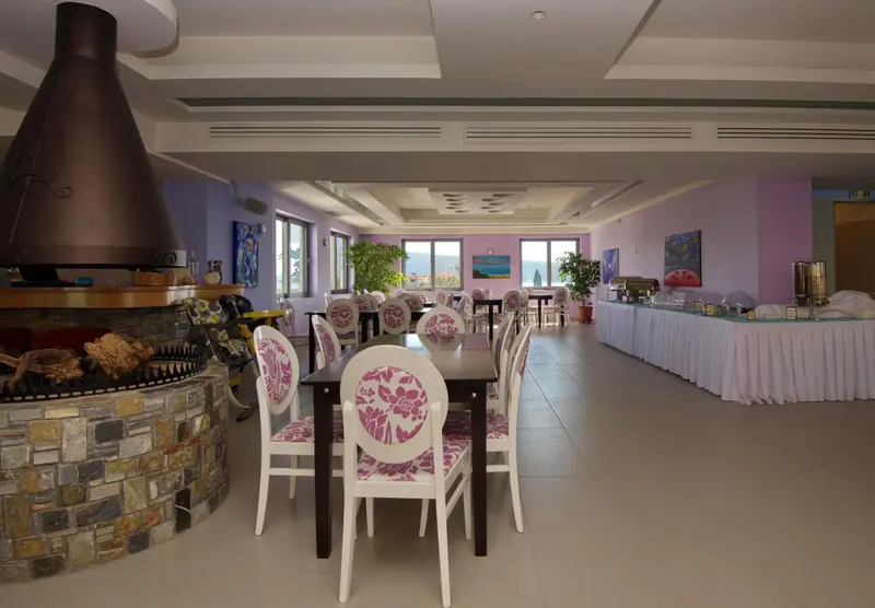 Une salle lumineuse avec des tables et des chaises est décorée d'une cheminée en pierre et de plantes.