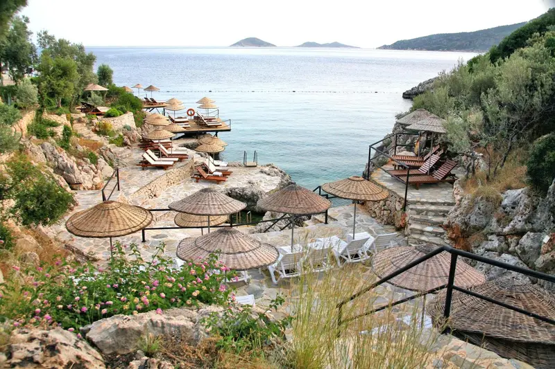 Terrasse ensoleillée avec transats et parasols au bord de la mer.
