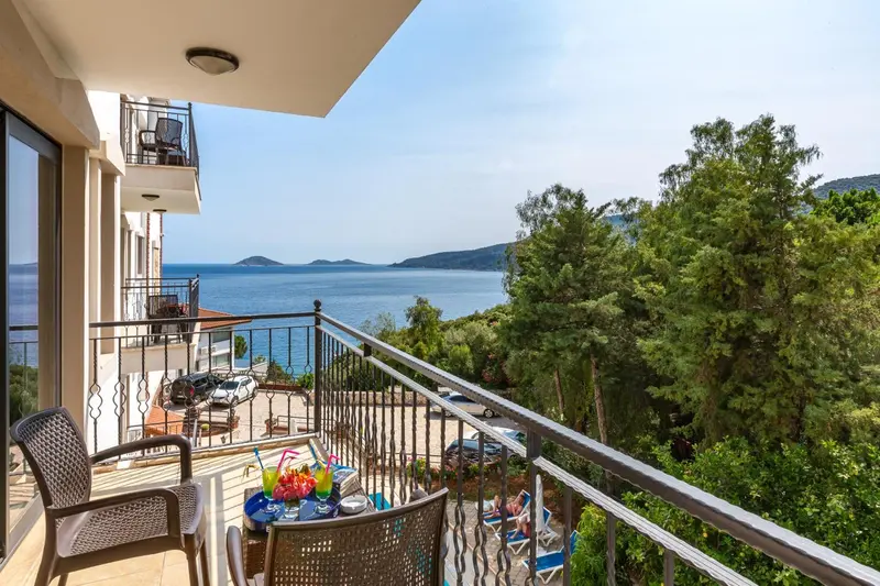 Vue d'un balcon avec mobilier et une vue sur la mer et la végétation.